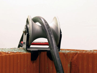 The cable guide roller - shaft inside edge is ideally suited for mounting on the edge of a shaft or on steps to pull cables gently around corners with the least possible resistance. Example photo showing roller mounted to the corner of a brick wall.
